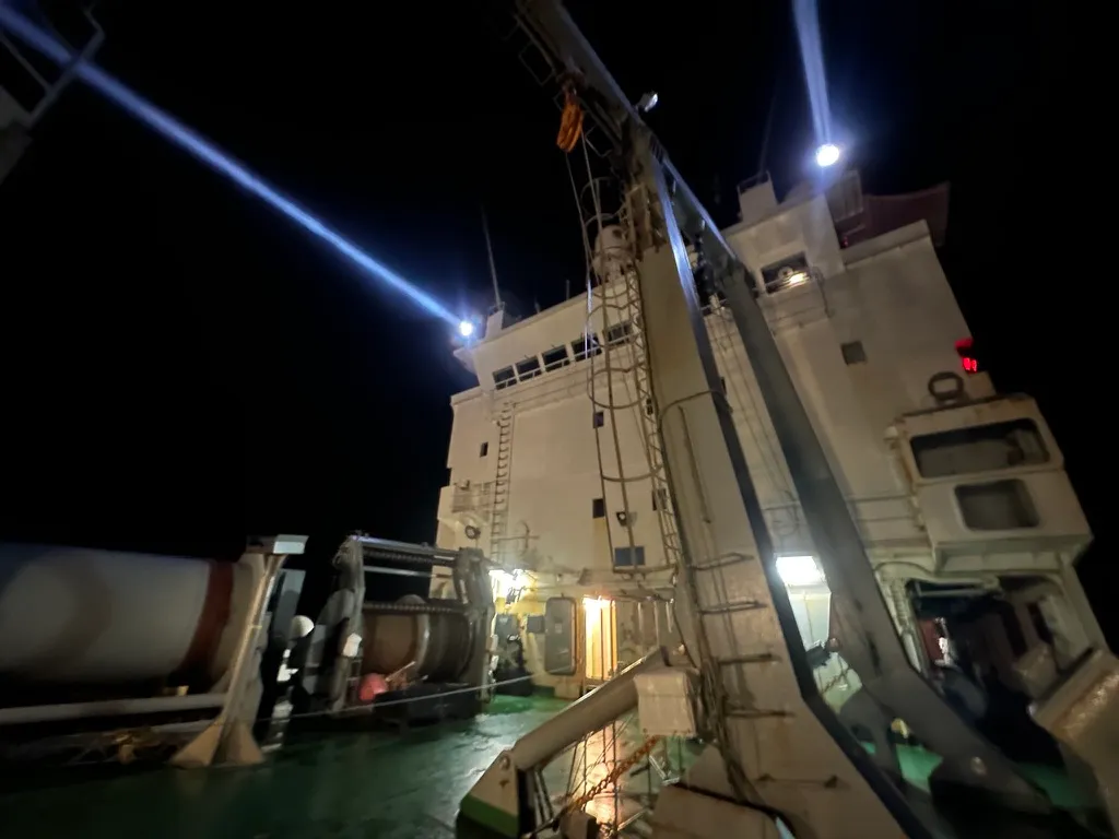 Night operations on deck during a NORSE cruise, with searchlights cutting through the polar darkness.